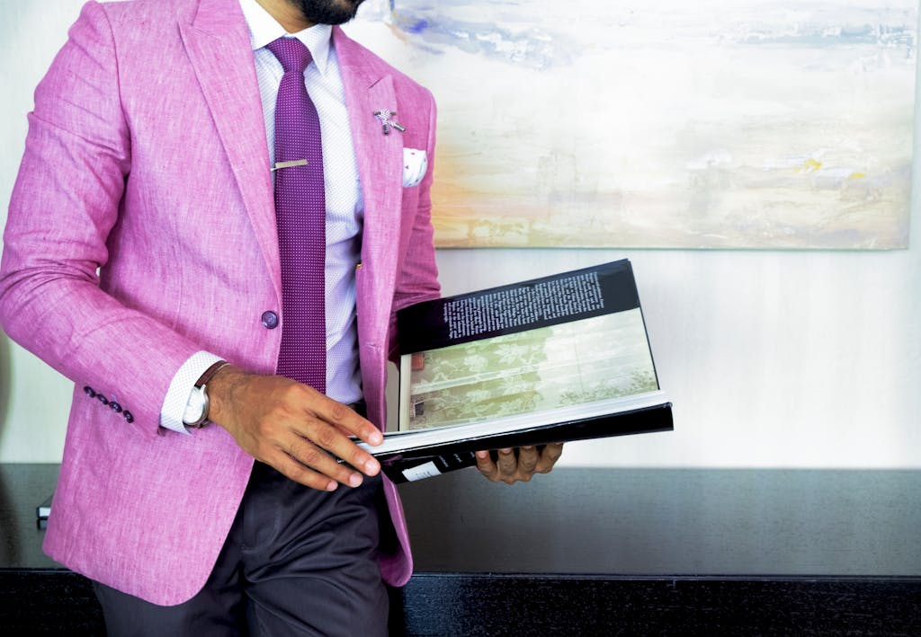A businessman in a pink suit holding a book, symbolizing success and professionalism.